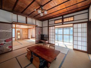 sala de estar con mesa de madera y ventanas en Smart House Kominka, en Atami