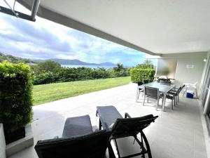 a patio with a table and chairs and a view at Hamilton Island Poinciana 008 Ground Floor 2bedrooms Free Buggy in Hamilton Island