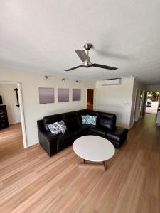 uma sala de estar com um sofá preto e uma mesa em Hamilton Island Poinciana 008 Ground Floor 2bedrooms Free Buggy em Hamilton Island