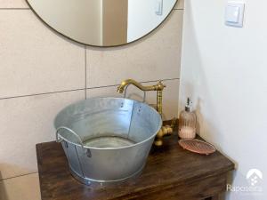 ein Waschbecken mit einem Metalleimer und einem Spiegel in der Unterkunft Raposeira Country House in Calheta