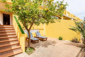 a yellow house with two chairs and an orange tree at Family house on the beach for holidays and temporary workers at Beach Sagunto Valencia in Sagunto