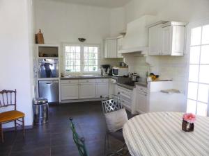 uma cozinha com armários brancos e uma mesa em Domaine avec Piscine em Grans