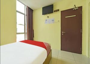 - une chambre avec un lit et une porte avec une télévision dans l'établissement South City Hotel @ Bandar Mahkota Cheras, à Kuala Lumpur