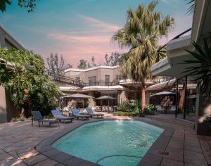 a swimming pool with lounge chairs and a resort at Villa Africa Boutique Hotel & Spa in Pretoria