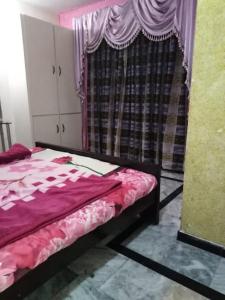 1 dormitorio con 1 cama y una ventana con cortinas en Jalwa Residential, en Murree