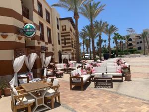 a patio with lounge chairs and tables and palm trees at PortghalibFlat in Port Ghalib