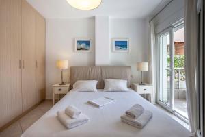 a bedroom with a large white bed with two towels at Seapalm House in Hanioti