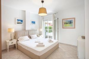 a white bedroom with a bed and a window at Seapalm House in Hanioti