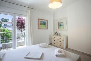 a bedroom with a white bed and a large window at Seapalm House in Hanioti