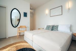 a bedroom with a white bed and a mirror at Melianthos Villas in Vathi