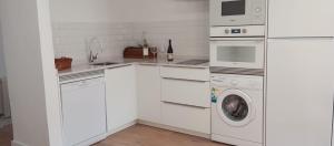 a kitchen with white cabinets and a washer and dryer at El Cantón del Cerrillo in Cornago