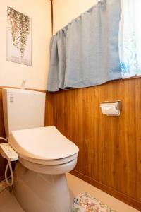 a bathroom with a white toilet and a window at 広島駅北口 古民家House 一軒家貸切り 自転車2台レンタル無料 in Hiroshima