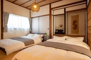 a bedroom with two beds and a large mirror at 広島駅北口 古民家House 一軒家貸切り 自転車2台レンタル無料 in Hiroshima