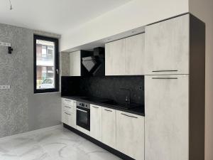een keuken met witte kasten, een gootsteen en een raam bij Сарафово Лукс Тераса Първа Линия in Sarafovo