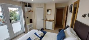 1 dormitorio con cama, ventana y puerta en Charnwood Guest House en Lyme Regis