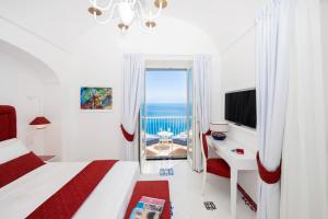 una camera da letto con un letto e una finestra con vista sull'oceano di AMORE RENTALS - Villa Blu a Praiano