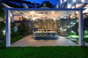 un patio con tavolo e sedie sotto un pergolato di notte di AMORE RENTALS - Villa Blu a Praiano
