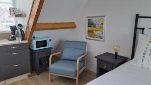 a bedroom with a bed and a chair and a tv at studio B&B Zeeuws licht in Westkapelle