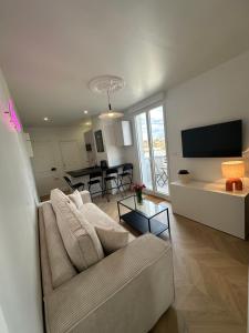ein Wohnzimmer mit einem Sofa, einem TV und einem Tisch in der Unterkunft Appartement, bel aperçu Tour Eiffel in Rueil-Malmaison
