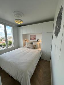 ein Schlafzimmer mit einem großen Bett und einem Fenster in der Unterkunft Appartement, bel aperçu Tour Eiffel in Rueil-Malmaison
