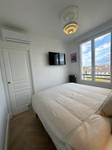 a white bedroom with a bed and a window at Appartement, bel aperçu Tour Eiffel in Rueil-Malmaison