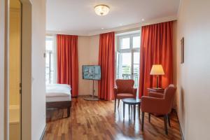 Habitación de hotel con cama y cortinas rojas en Hotel Schweizerhof Basel, en Basilea