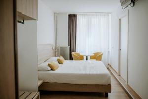a white bedroom with a bed and a table at Hotel Venezia in Trento