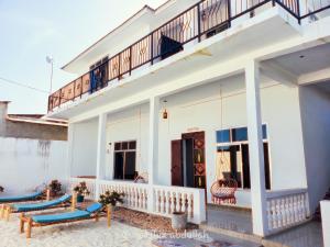 uma casa branca com varanda e almofadas azuis em Raha house em Nungwi