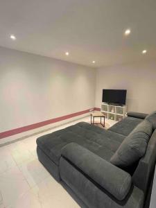 1 sofá grande en una sala de estar con TV de pantalla plana. en Douce nuit en Saint-Nicolas-dʼAliermont