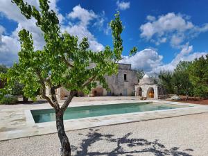 uma árvore em frente a uma casa com piscina em Pietra Pesara em Locorotondo