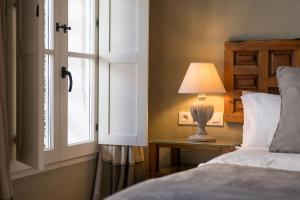 a bed with a lamp on a table next to a window at Hotel La Casa del Califa in Vejer de la Frontera