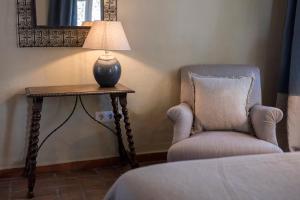 una lámpara sentada en una mesa junto a una silla en Hotel La Casa del Califa, en Vejer de la Frontera