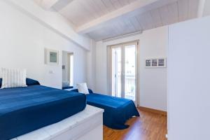 ein weißes Schlafzimmer mit einem blauen Bett und einem Fenster in der Unterkunft Appartamento Duplex Cairoli - MyHo Casa in Porto San Giorgio