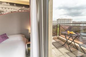 Hotel Inn Design Paris Place d’Italie (ex Timhotel) في باريس: غرفة بسرير وشرفة مطلة
