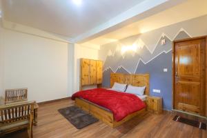 um quarto com uma cama de madeira e um cobertor vermelho em Luvya Retreats Hotel em Manali
