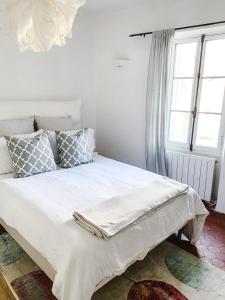 a bedroom with a white bed with pillows and a window at La Belugue in Beaumont-de-Pertuis