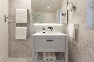 a white bathroom with a sink and a mirror at Bayside Retreat in Sydney