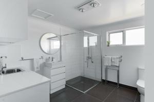 baño blanco con ducha y lavamanos en Battery Point Beauty, en Hobart