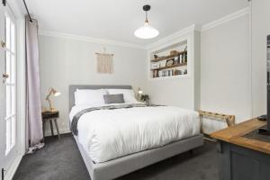 a white bedroom with a bed and a desk at Bluestone Cottage Launceston in Launceston