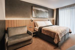 a bedroom with a bed and a chair at Atrium Hotel - Family friendly in Vysoke Tatry - Novy Smokovec