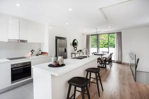 a kitchen with white counter tops and stools at Bream Penthouse in Sydney