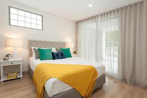 1 dormitorio con 1 cama con manta amarilla y ventana en Bream Penthouse en Sídney