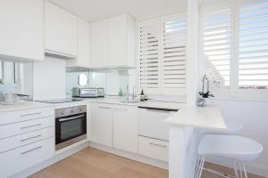 a white kitchen with white cabinets and a counter at Centennial Retreat in Sydney