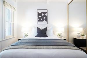 a bedroom with a large white bed with two lamps at Woollahra Contemporary in Sydney
