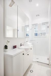 a white bathroom with a sink and a shower at Woollahra Contemporary in Sydney