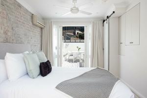 a bedroom with a white bed and a brick wall at Wharf House Woolloomooloo in Sydney