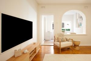een woonkamer met een flatscreen-tv aan de muur bij Coastal Calm Coogee in Sydney