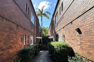 an alley between two brick buildings with a palm tree at Coastal Calm Coogee in Sydney