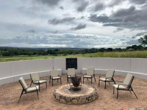 a group of chairs and a fire pit on a patio at 7th Hole Golf Lodge in Modimolle