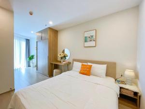 - une chambre avec un grand lit blanc et un oreiller orange dans l'établissement Ông Chú Condotel - The Sóng 5 Stars Vũng Tàu, à Vung Tau